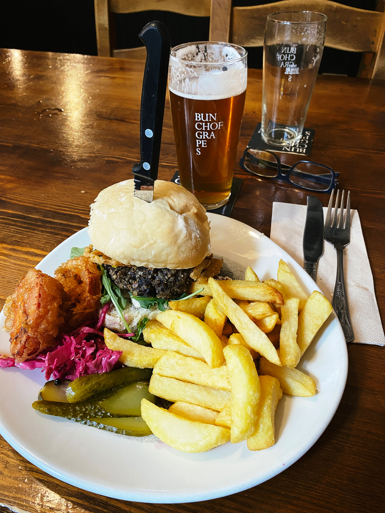 Plate containing vegan burger, chips and pickles
